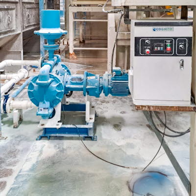 Blaue elektrische Doppelmembranpumpe und angeschlossener Rohrleitung in einer Produktionsanlage f&uuml;r Farben und Lacke. Neben der Pumpe befindet sich ein Steuerkasten zur Bedienung und &Uuml;berwachung der Anlage.