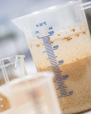 Geflocktes Abwasser mit Leimresten in einem Messbecher