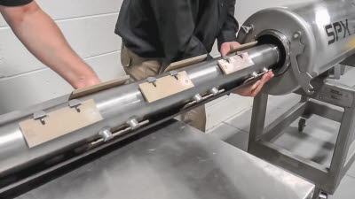 Zwei Servicetechniker ziehen die mit Schabern besetze Welle aus dem Geh&auml;use des Schabew&auml;rmetauschers